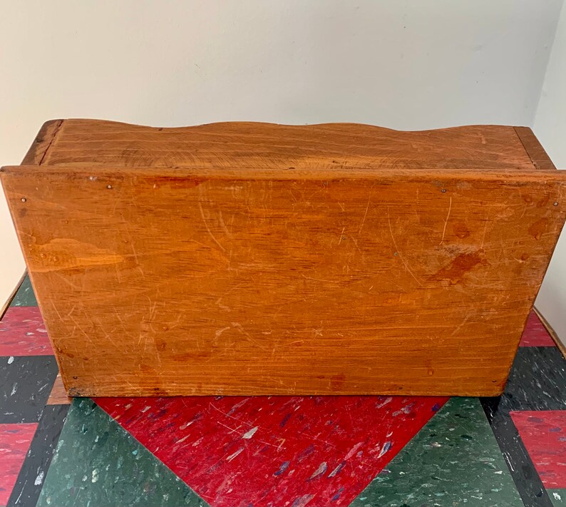 May include: A wooden box with a simple design. The box has a light brown color and a smooth surface. The box is made of wood and has a rectangular shape.