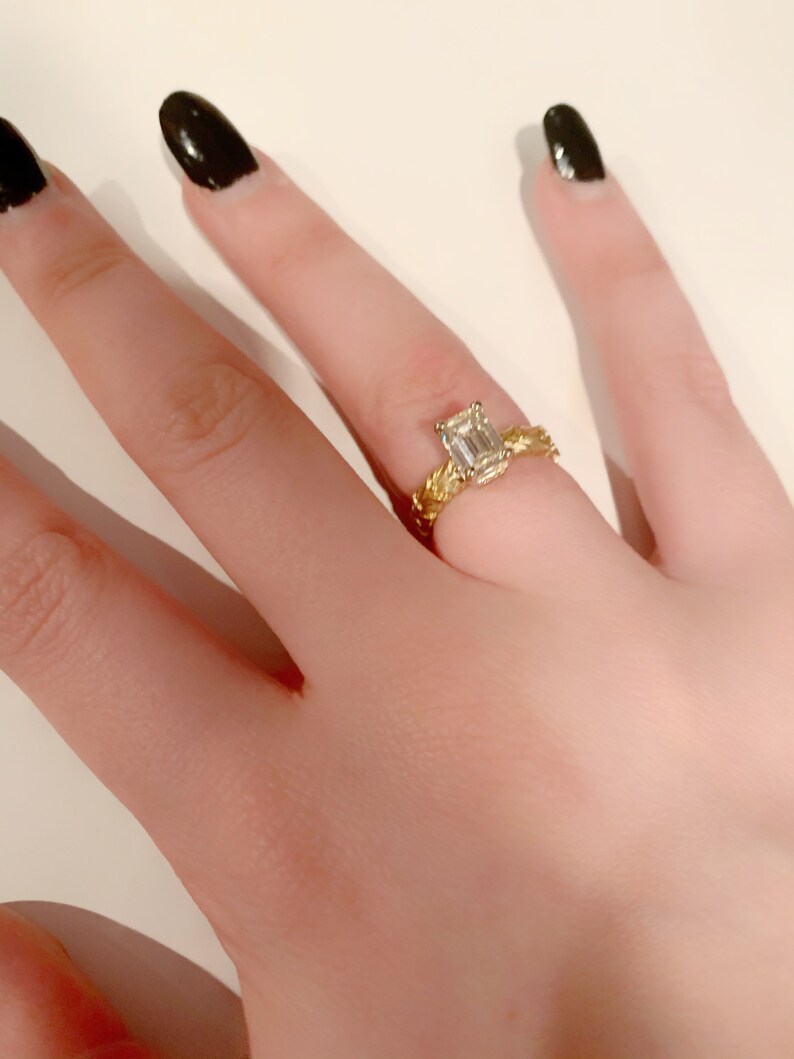 May include: A gold ring with a braided band and an emerald-cut diamond.