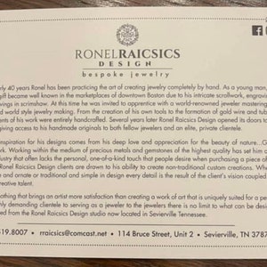 May include: A white card with brown text describing Ronel Raicsics Design, a bespoke jewelry company. The card includes the company's contact information: 617.519.8007, rraicsics@comcast.net, 114 Bruce Street, Unit 2, Sevierville, TN 37876.