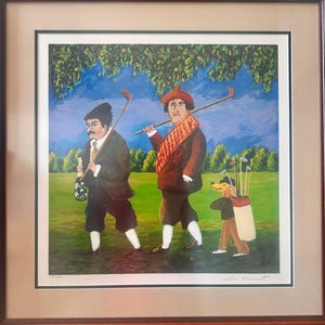 Könnte beinhalten: Gerahmter Druck einer Golfszene mit drei Figuren auf einem grünen Feld unter blauem Himmel. Zwei Männer in Golfkleidung gehen, einer trägt eine Flasche. Ein Hund trägt eine Golftasche. Das Kunstwerk ist signiert.