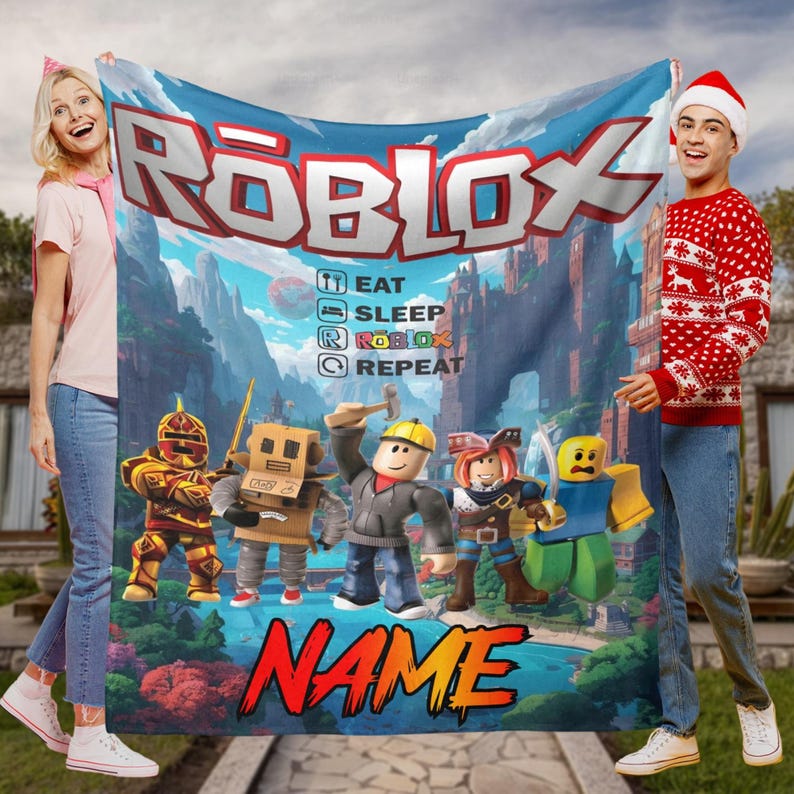 May include: A large, rectangular Roblox-themed blanket with the Roblox logo and characters. The blanket has a blue background with a castle and mountain scene. Text on the blanket reads "EAT, SLEEP, ROBLOX, REPEAT" and "NAME".