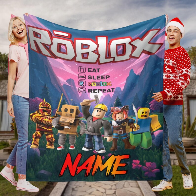 May include: A Roblox blanket with the Roblox logo, the text "EAT SLEEP ROBLOX REPEAT," and Roblox character illustrations. The blanket has a colourful design with a mountain and sky background, and the word "NAME" in large, red letters.