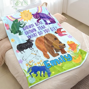 May include: A light blue fleece blanket featuring colorful illustrations of a brown bear, purple cat, green frog, black sheep, white dog, blue horse, red bird, yellow fish, and a yellow sun. The text reads: BROWN BEAR, BROWN BEAR, WHAT DO YOU SEE? and EMILY.