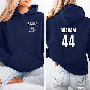 May include: A navy blue hooded sweatshirt featuring a white graphic on the front chest that reads BRIAR UNIVERSITY HOCKEY with crossed hockey sticks. The back of the hoodie displays the name GRAHAM in white text above the large white number 44.