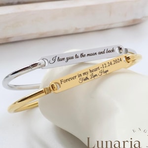 Puede incluir: Dos pulseras grabadas. Una es plateada con la inscripción "I love you to the moon and back". La otra es dorada, con la inscripción "Forever in my heart -12.24.2024 Faith, Love, Hope."