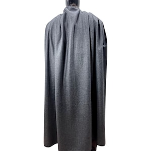 Puede incluir: Una taza de cer&aacute;mica blanca con un asa negra y el texto "But First, Coffee" en negrita negra. La taza se encuentra sobre un fondo borroso, sugiriendo un ambiente acogedor.