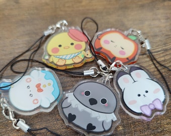 May include: A collection of five acrylic charms featuring cute cartoon characters. The charms include a yellow chick, a red apple, a white bunny, a gray owl, and a white bunny with a pink bow. Each charm has a black lanyard attached.