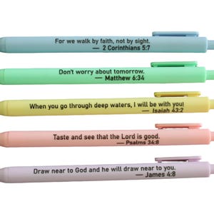 May include: Five retractable ballpoint pens in pastel colors: light blue, mint green, pale yellow, soft peach, and lavender. Each pen features a black clip and is printed with a unique Bible verse and reference in black sans-serif text.