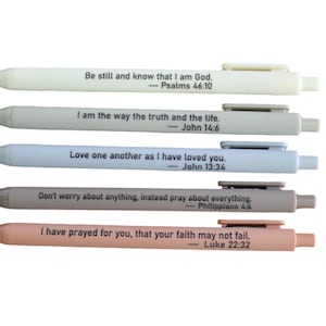 May include: Five pens in various pastel colors, each with a Bible verse printed in black. The pens are light beige, gray, light blue, taupe, and peach. The text includes verses from Psalms, John, and Luke.
