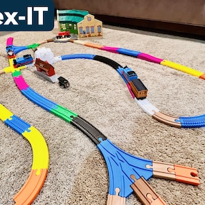 May include: A colorful toy train set with a track made of various colors, including blue, yellow, and pink. The set includes a train, buildings, and a bridge. The text "Flex-IT" is visible in the top left corner.
