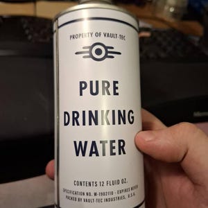May include: A white cylindrical can with the text "PURE DRINKING WATER" and "PROPERTY OF VAULT-TEC." The can contains 355 ml. The can has a silver cap and a blue and white design.