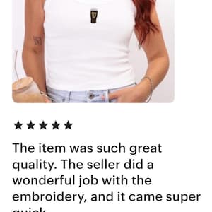May include: White ribbed vest top with a small embroidered design. The top has thin straps and a scoop neckline. The image also includes a review of the item.