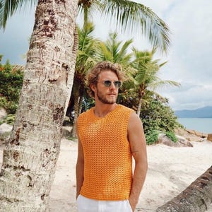 Pu&ograve; includere: Un top smanicato all'uncinetto di colore arancione brillante con un motivo a maglia testurizzato e scollo rotondo, abbinato a pantaloni bianchi semplici. Il top presenta un design a maglia aperta coerente su tutta la superficie.