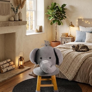 May include: A gray crocheted elephant stool featuring a round seat with a plush elephant head, large ears, and a trunk. The stool has four light-colored wooden legs with gray crocheted covers on the feet, providing a stable base for the seat.