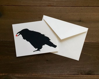 raven with a red berry in its beak greeting card