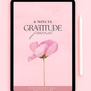 Puede incluir: Una tableta digital muestra un diseño floral rosa con el texto "6 Minute Gratitude Journal". Un lápiz óptico blanco descansa junto a la tableta. La portada del diario presenta una flor rosa y las palabras "With Inspirational Quotes by MK."