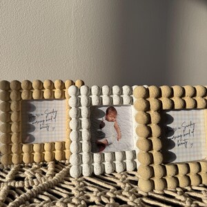 May include: Three decorative photo frames with a textured, beaded design. The frames are in shades of beige and white, with one holding a baby photo. The text "You're a Sunday morning kind of beauty" is visible on the other frames.