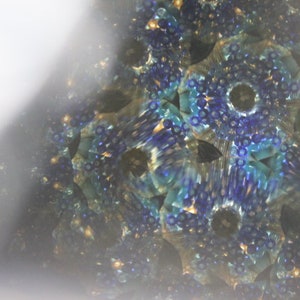 Pu&ograve; includere: Un'immagine di caleidoscopio con un motivo blu, verde e oro. L'immagine &egrave; composta da molte piccole forme ripetute.