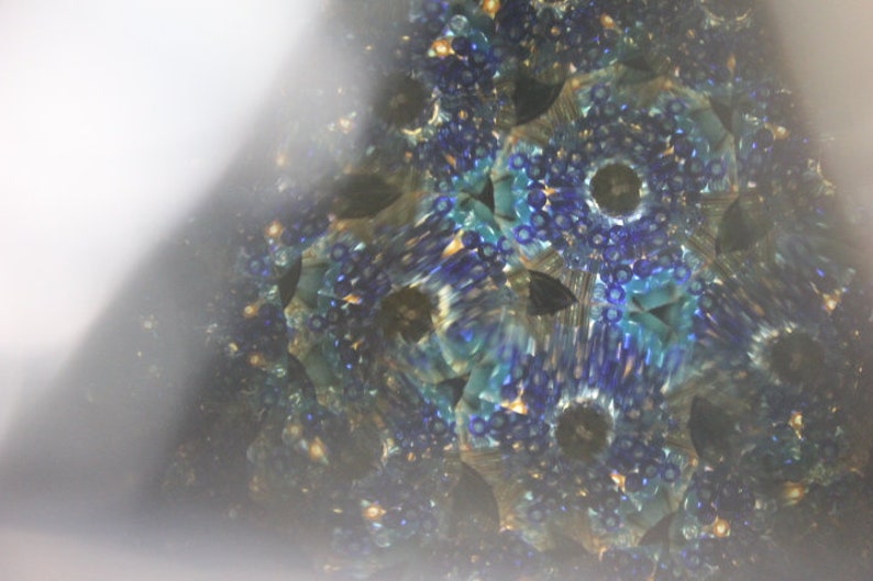 Pu&ograve; includere: Un'immagine di caleidoscopio con un motivo blu, verde e oro. L'immagine &egrave; composta da molte piccole forme ripetute.