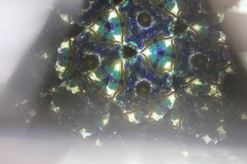 Pu&ograve; includere: Un'immagine di caleidoscopio con un motivo ripetitivo di blu, verde e oro. L'immagine &egrave; sfocata e fuori fuoco.