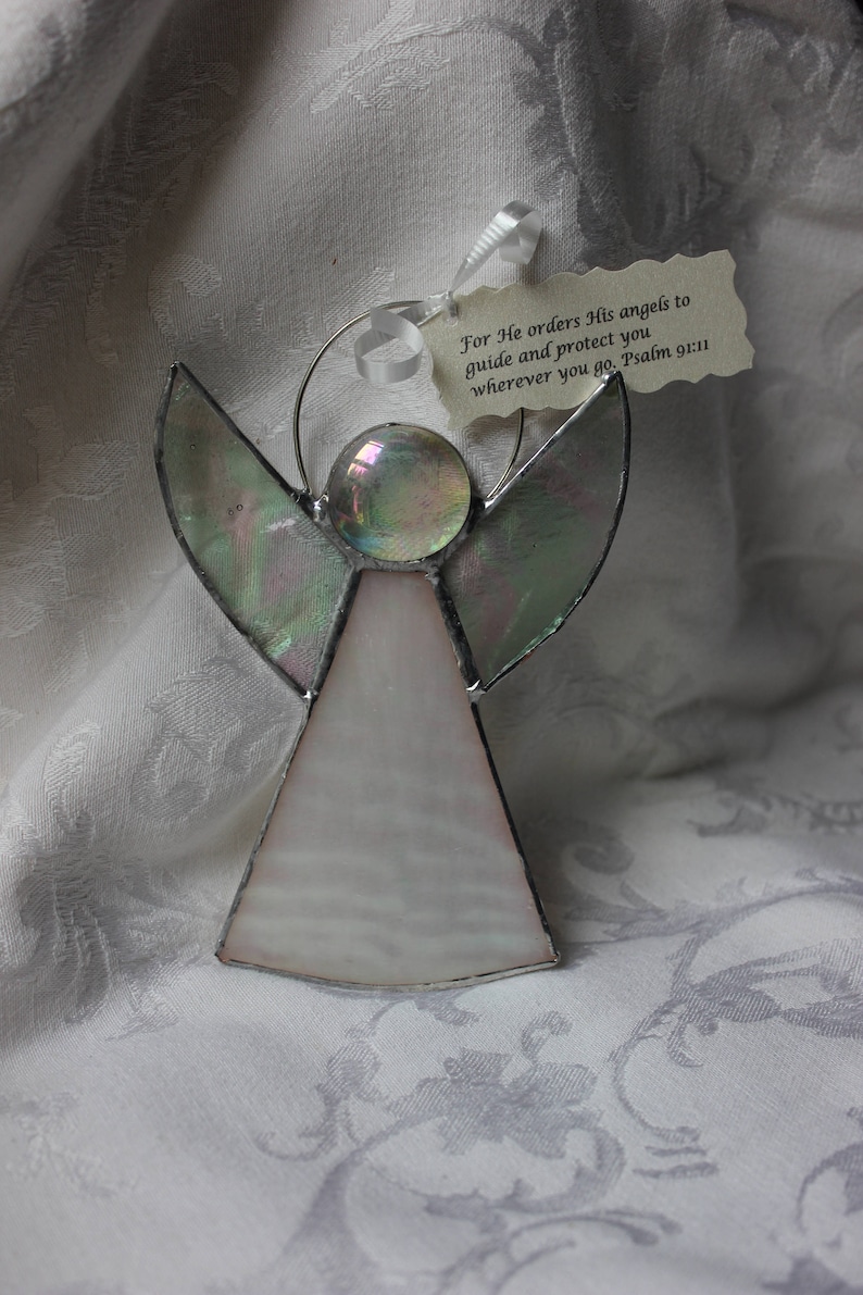 May include: A stained glass angel ornament with iridescent wings and a white body. The ornament has a halo and a quote from Psalm 91:11, "For He orders His angels to guide and protect you wherever you go. Psalm 91:11".