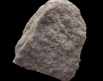 May include: A close-up of a gray rock against a black background. The rock has a rough, textured surface with various shades of gray and white. The shape is irregular, with a slightly rounded top and a jagged edge.