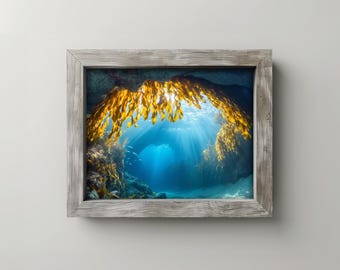 Pode incluir: Fotografia emoldurada de uma cena subaquática. A imagem captura uma vibrante caverna subaquática azul, iluminada por raios de sol. Algas douradas pendem do teto da caverna, criando um arco. A moldura é de madeira cinza envelhecida.