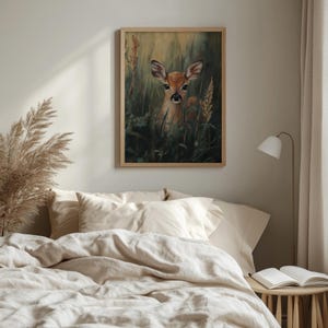 May include: A framed art print featuring a deer in a field of tall grass. The artwork has a natural wood frame and depicts a fawn with brown fur and large ears. The background is a mix of green and yellow hues.