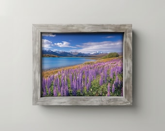May include: A framed landscape print featuring a vibrant field of purple lupine flowers in front of a lake and snow-capped mountains under a blue sky. The frame is made of weathered gray wood.