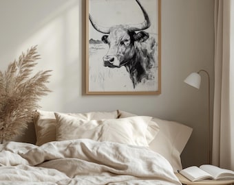 Pode incluir: Um desenho a preto e branco emoldurado da cabeça de um touro com grandes chifres. A obra de arte é exibida acima de uma cama com roupa de cama bege. O quarto tem uma paleta de cores neutras, com uma lâmpada e uma mesa lateral visíveis.