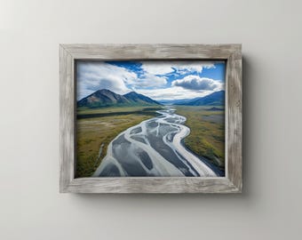 May include: A framed landscape photograph featuring a winding river flowing through a valley. The image showcases a mountain range under a cloudy blue sky. The frame is made of weathered, light gray wood.