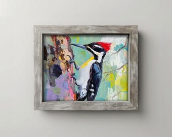 Pode incluir: Pintura emoldurada de um pica-pau empoleirado num tronco de árvore. A ave tem uma crista vermelha, plumagem preta e branca e um bico longo. A obra apresenta pinceladas vibrantes e um aspeto texturizado.