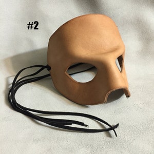 May include: A tan leather masquerade mask with eye and nose cutouts and black leather ties. #2