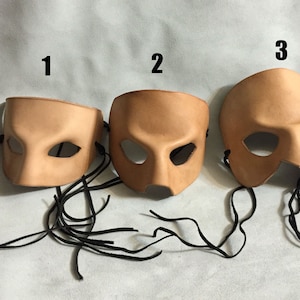 May include: Three leather masks with black ties. The masks are numbered 1, 2, and 3. The masks are all the same color, a light brown.
