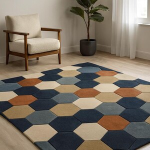 Puede incluir: Una alfombra geométrica con un patrón de panal en tonos azul marino, azul, beige y óxido. La alfombra está colocada sobre un suelo de madera clara, con una silla de madera y una planta en maceta en el fondo.