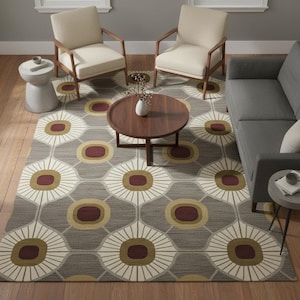 May include: A gray area rug with a repeating floral pattern in white, gold, and burgundy. The rug is in a living room setting with two cream-colored armchairs, a gray sofa, and a wooden coffee table. The rug's dimensions are approximately 8 x 10 feet.