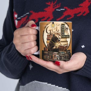 Può includere: Tazza in ceramica bianca con un orso bruno che legge un libro, con le parole "Get Lit" in un design circolare. L'orso indossa una catena d'oro ed è circondato da pile di libri. La tazza ha una combinazione di colori marrone e oro.
