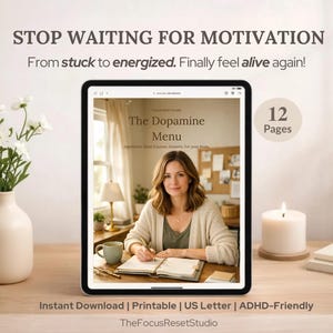Puede incluir: Una tableta digital muestra "The Dopamine Menu" con una mujer escribiendo. La imagen incluye texto: "Stop Waiting for Motivation" y "From stuck to energized. Finally feel alive again!" Un jarrón con flores blancas, una vela y una planta están sobre una superficie de madera.