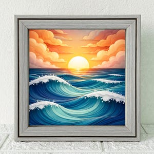 May include: Square framed artwork depicting a sunset over the ocean. The sun is a bright yellow orb, with orange and pink clouds above the blue waves. The artwork is framed in a light gray wooden frame.