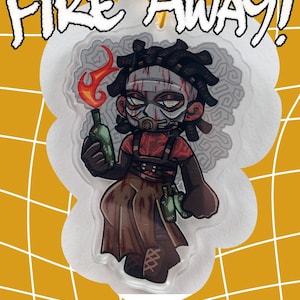 May include: A cartoon-style acrylic charm featuring a character holding a flaming bottle. The character wears a mask and a red shirt, with the words "FIRE AWAY!" above. The background is yellow with a white grid.