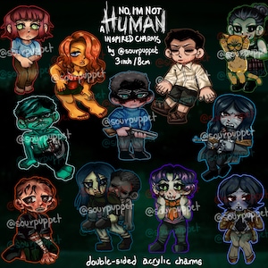 May include: A collection of double-sided acrylic charms featuring stylized, spooky characters. The charms are inspired by the phrase "No, I'm Not Human." Each charm is approximately 3 inches (8 cm) in height and features unique designs with various colors and details.