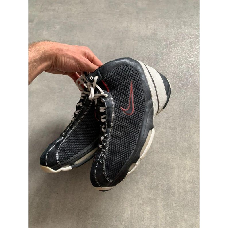 Puede incluir: Zapatillas deportivas Nike Max Air negras y blancas con detalles rojos. Las zapatillas tienen un dise&ntilde;o de malla en los laterales y el logo de Nike swoosh en rojo. Cordones blancos.