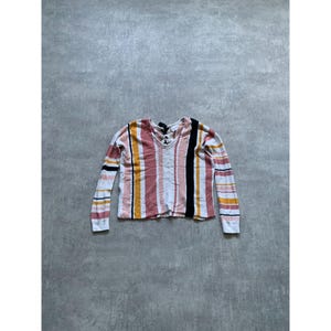 May include: A long-sleeved shirt with a V-neck and a vertical striped pattern. The stripes include white, black, pink, yellow, and orange. The shirt is made of a soft material.