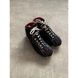 Puede incluir: Un par de zapatillas altas negras con cordones blancos y detalles rojos. Las zapatillas tienen un dise&ntilde;o elegante con el texto "MAX AIR" visible en el lateral. El forro interior es rojo.