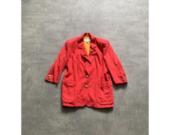 May include: A red blazer with gold buttons and three-quarter sleeves. The blazer has a classic design with a notched collar and two front pockets. The interior lining is a bright yellow color.