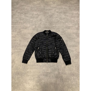 May include: Black quilted bomber jacket with a zip-up front, two front pockets, and a ribbed collar and cuffs. The jacket has a subtle sheen and a classic, versatile design.