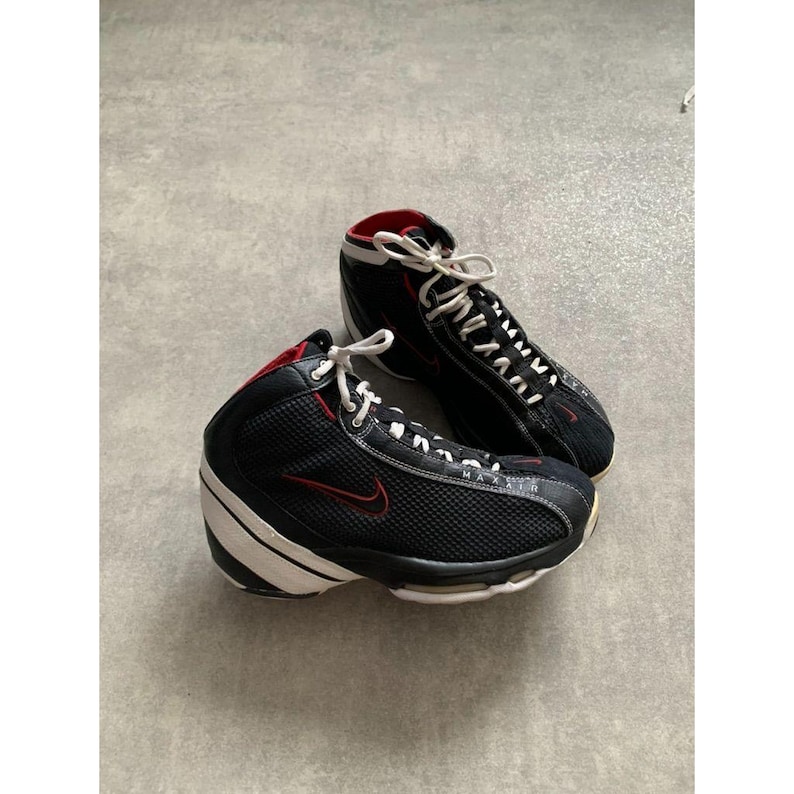 Puede incluir: Par de zapatillas deportivas altas negras y rojas con cordones y suelas blancas. Las zapatillas presentan un logotipo Nike swoosh rojo en el lateral y un forro interior rojo. Las suelas son blancas con detalles en negro.