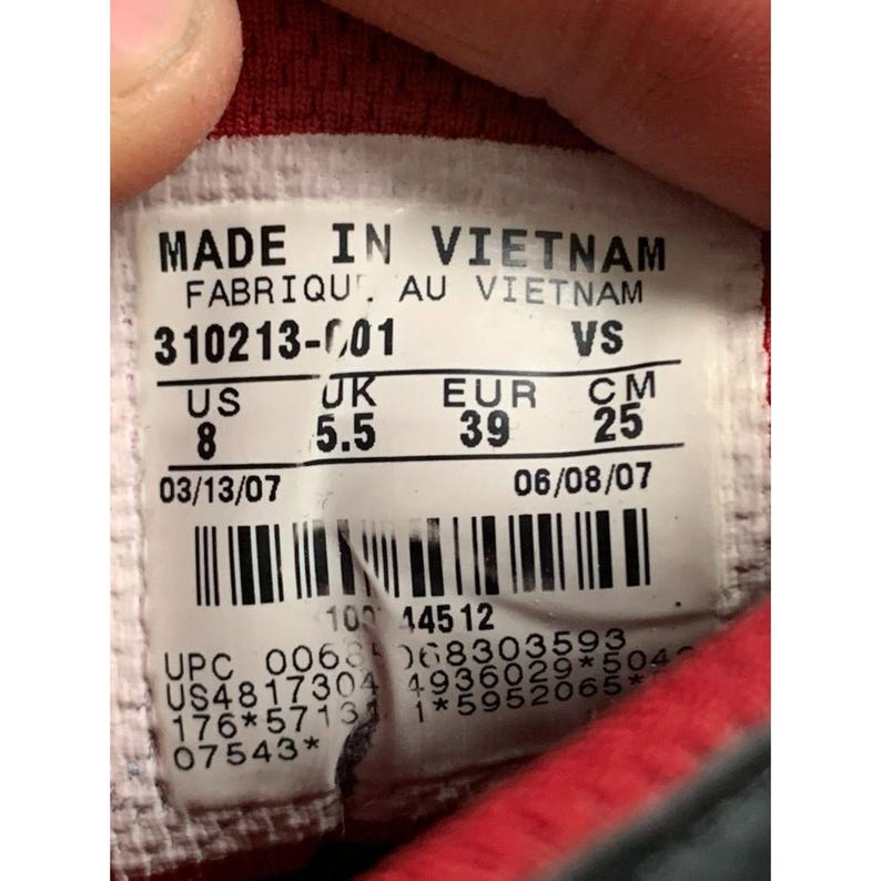 Puede incluir: Primer plano de una etiqueta de zapato con la inscripci&oacute;n "MADE IN VIETNAM". La etiqueta muestra detalles de tallas: US 8, UK 5.5, EUR 39 y 25 cm. Tambi&eacute;n incluye informaci&oacute;n de producci&oacute;n y c&oacute;digo de barras.