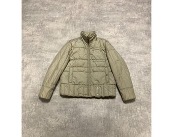 Pode incluir: Casaco acolchoado verde-oliva claro com gola alta e zíper de comprimento total. O casaco tem um design acolchoado, dois bolsos frontais e um fecho de botão na parte inferior. O casaco tem aproximadamente 61 cm de comprimento.