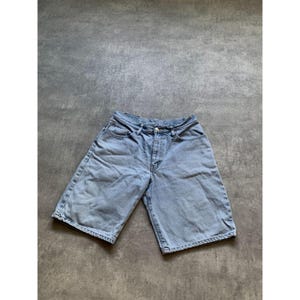 May include: Light blue denim shorts with a classic five-pocket design. The shorts have a button and zipper closure and a relaxed fit. The denim has a faded wash, giving them a vintage look. The shorts are suitable for casual wear.